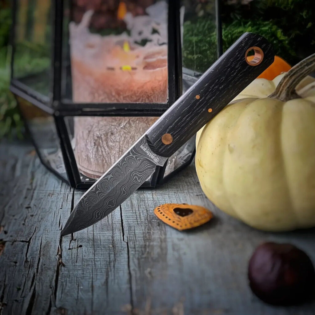Ein Messer auf einem Holztisch neben einem Kürbis.