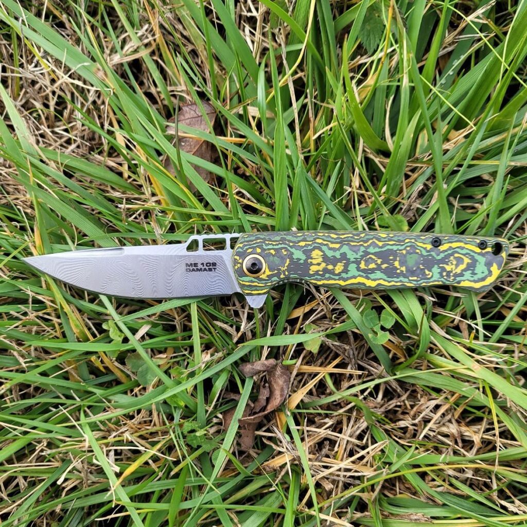 Ein grün-gelbes Messer, das im Gras liegt.
