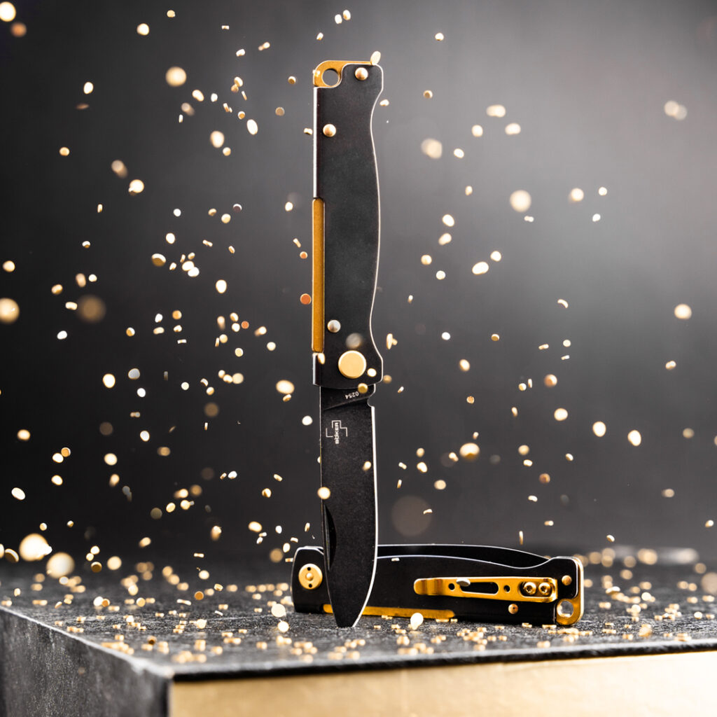 Ein schwarz-goldenes Messer, das auf einer goldenen Schachtel liegt.