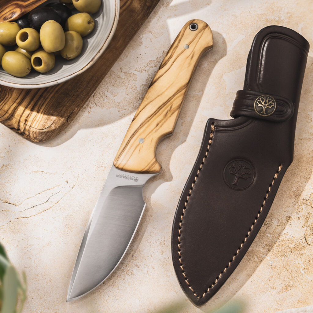 Ein Messer mit Oliven und Olivenöl auf einem Schneidebrett.