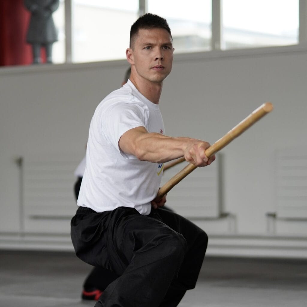 Martin Borter in Kung-Fu-Stellung mit Holzstock beim Üben von Kampfkünsten.